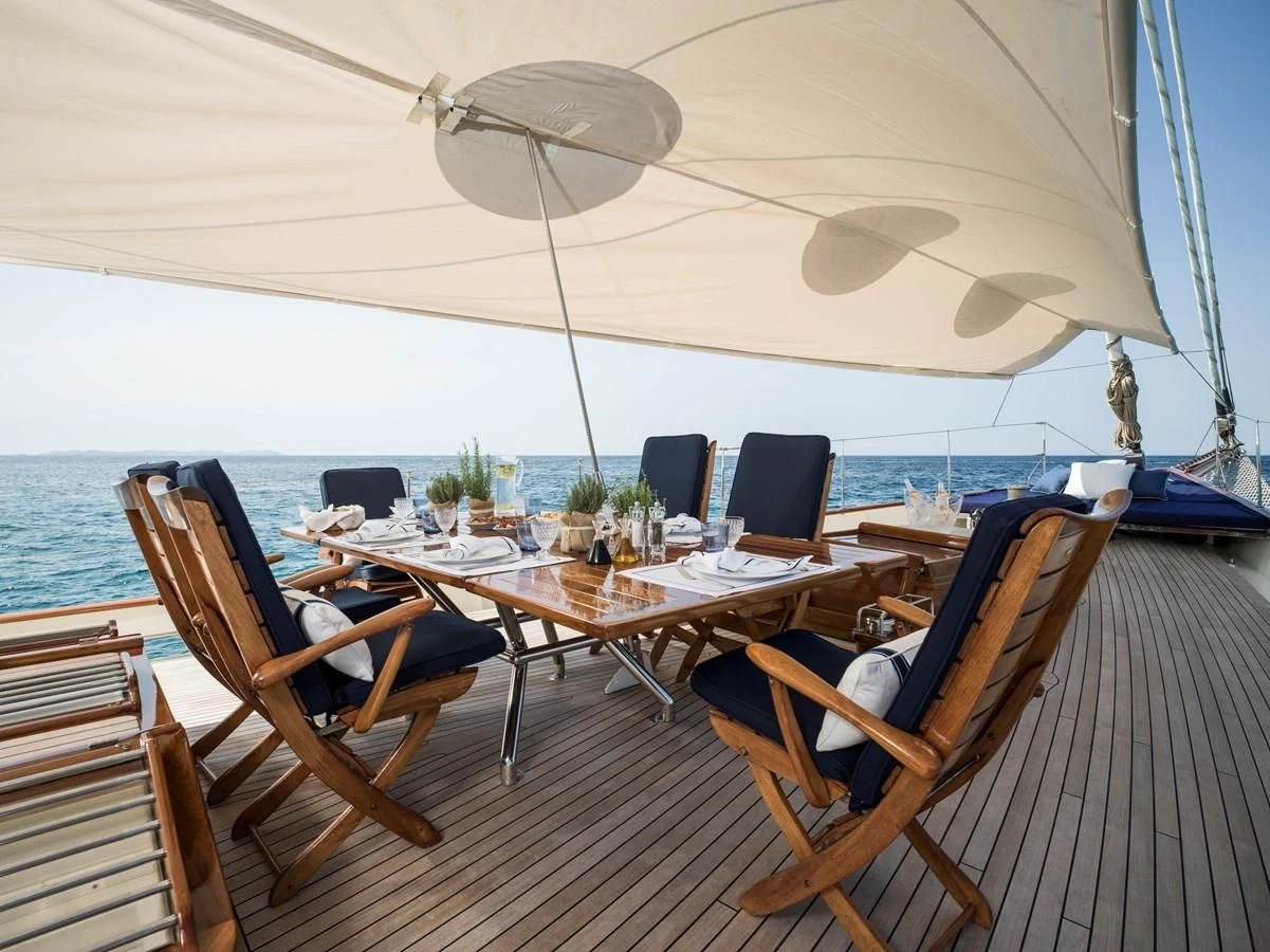 a table set for a meal on a deck with a view of the water aboard ALEXA OF LONDON Yacht for Sale