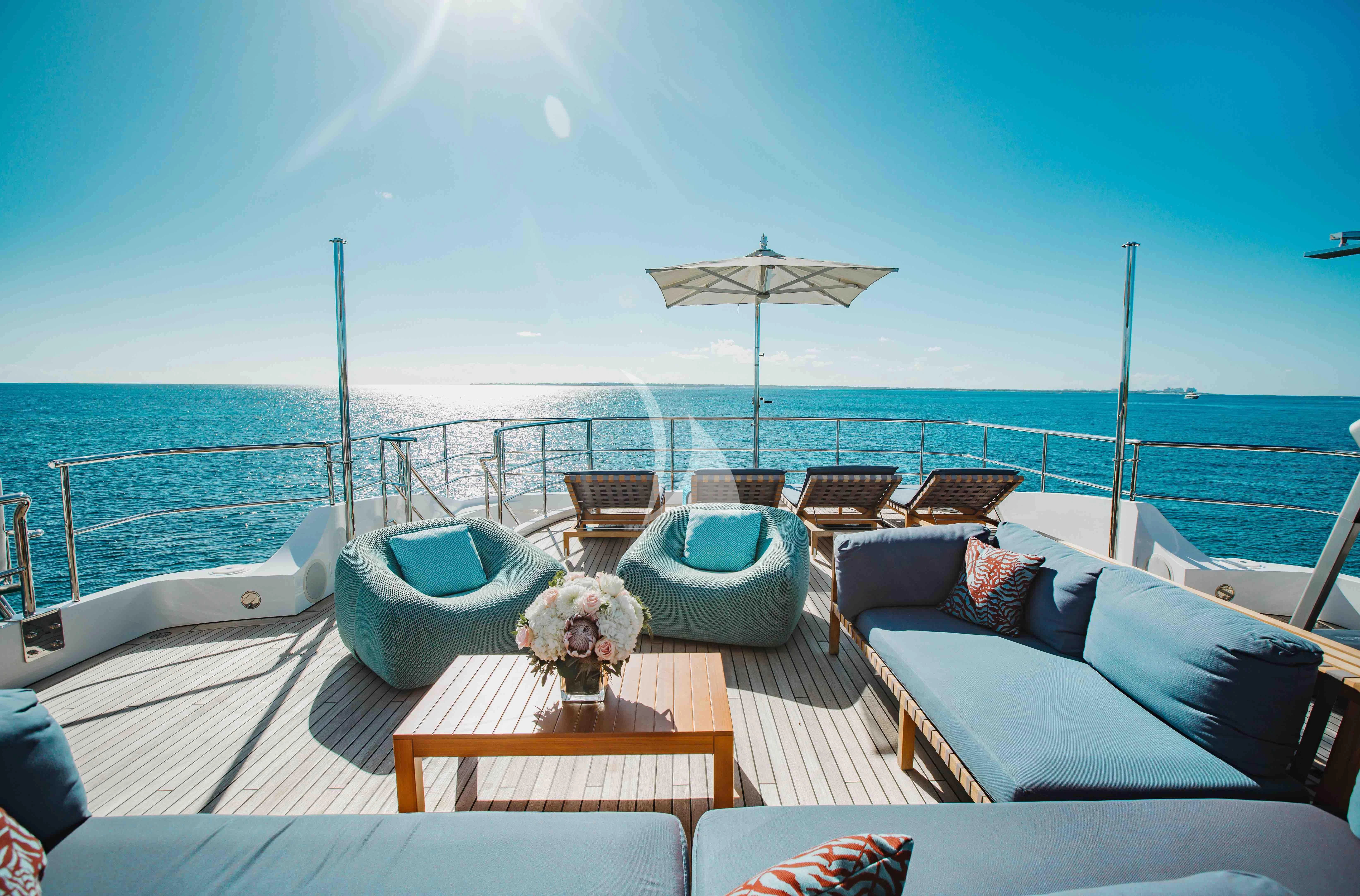 a lounge area with lounge chairs and umbrellas on a deck overlooking the ocean aboard COFINA Yacht for Sale