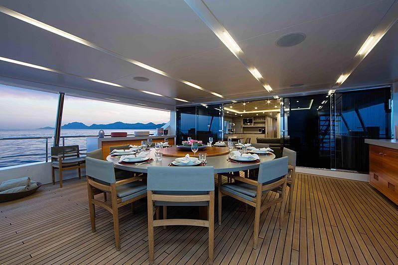 a large dining table with chairs and a large body of water in the background aboard COFINA Yacht for Sale