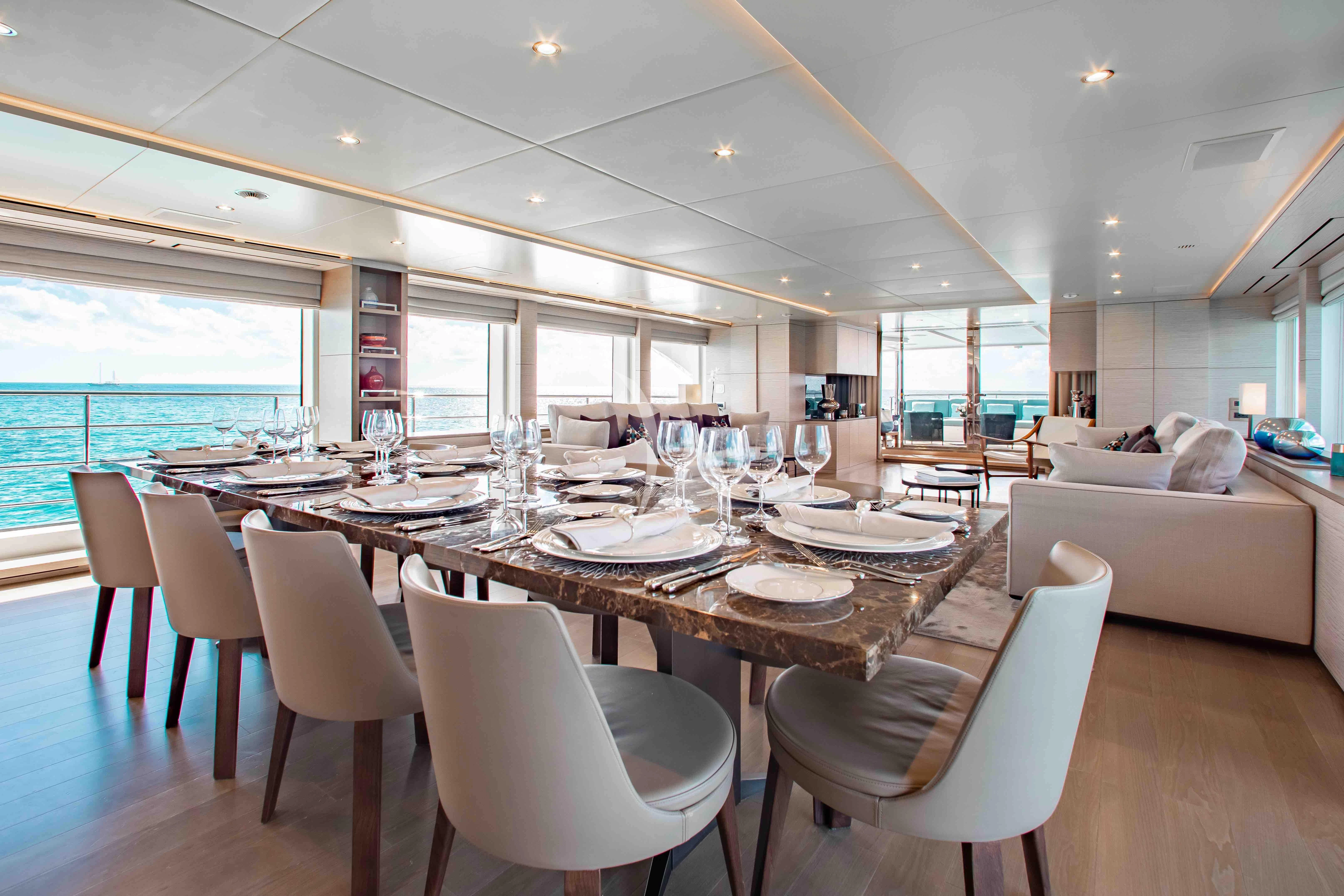 a large dining table with white chairs aboard COFINA Yacht for Sale