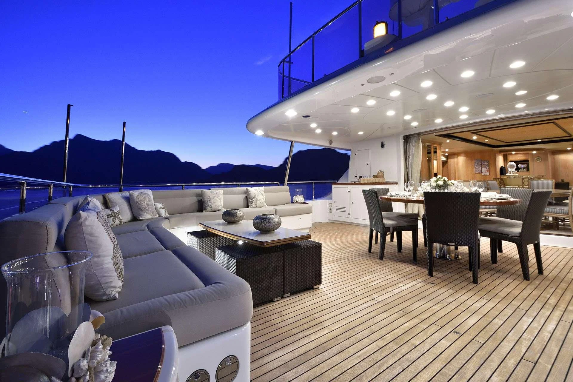 a large room with a table and chairs and a large mountain in the background aboard QUEST R Yacht for Sale