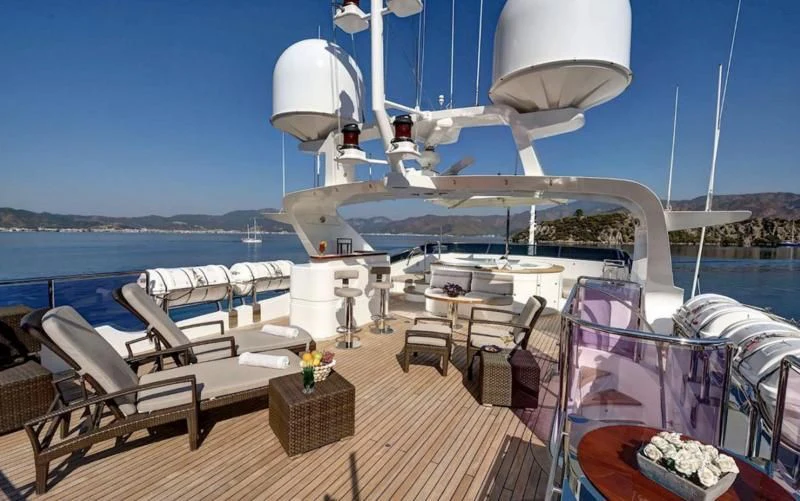 a deck with a table and chairs on it and a large white ship in the background aboard QUEST R Yacht for Sale