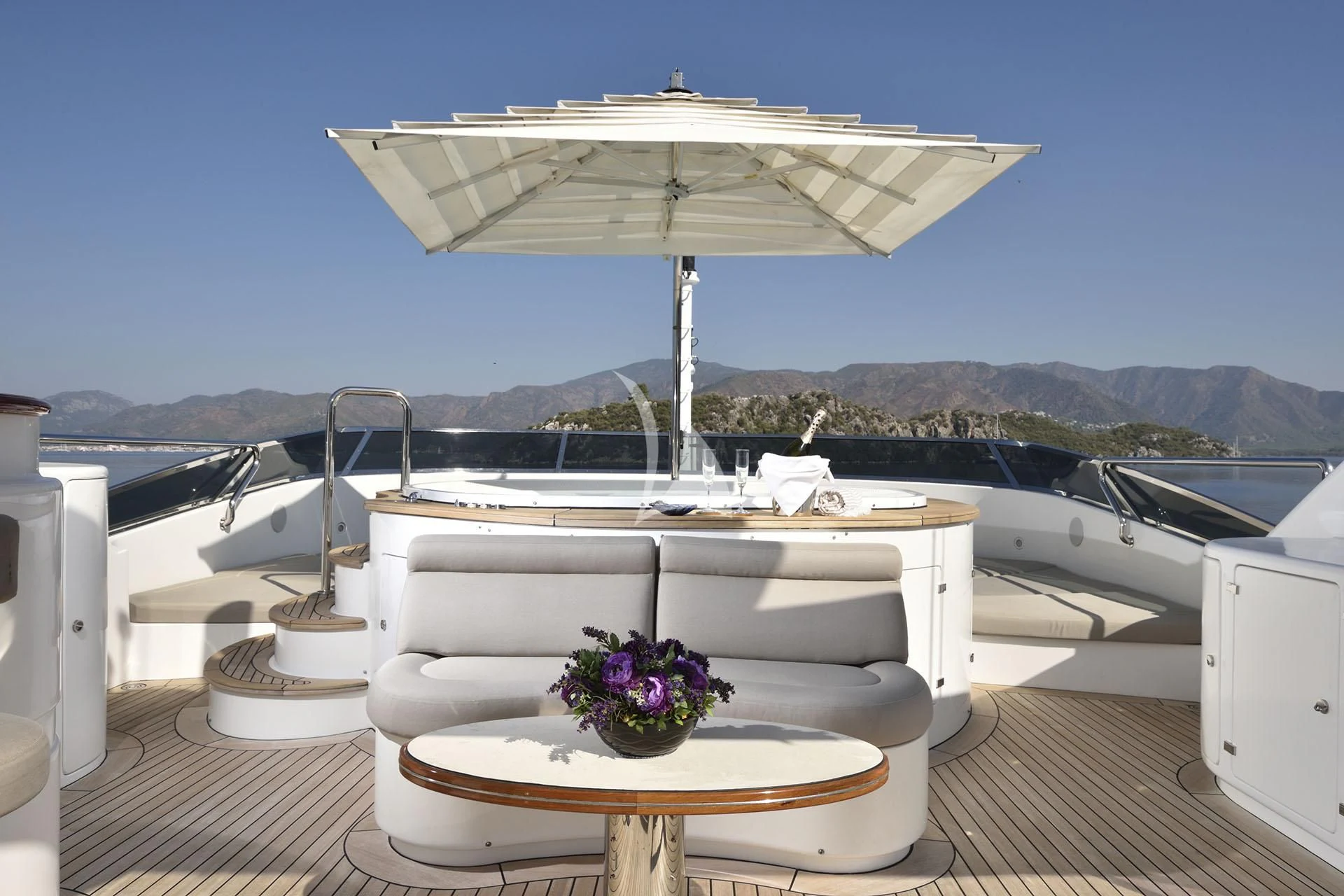 a white lounge chair with a white umbrella on a deck with a white table and white chairs and aboard QUEST R Yacht for Sale