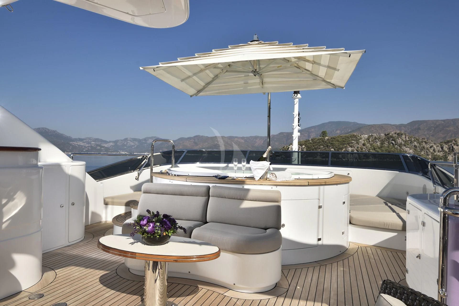 a white lounge chair next to a table and a white chair on a deck with a view of aboard QUEST R Yacht for Sale