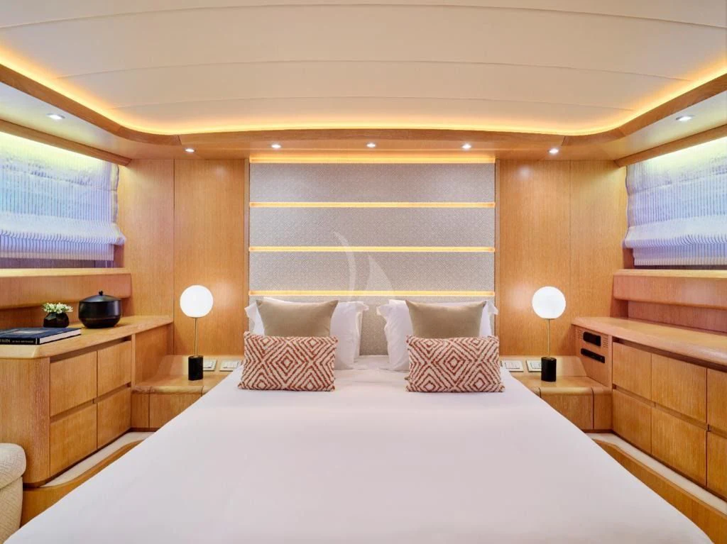 a bed with a white sheet and pillows in a room with wood cabinets aboard IRENE'S Yacht for Sale