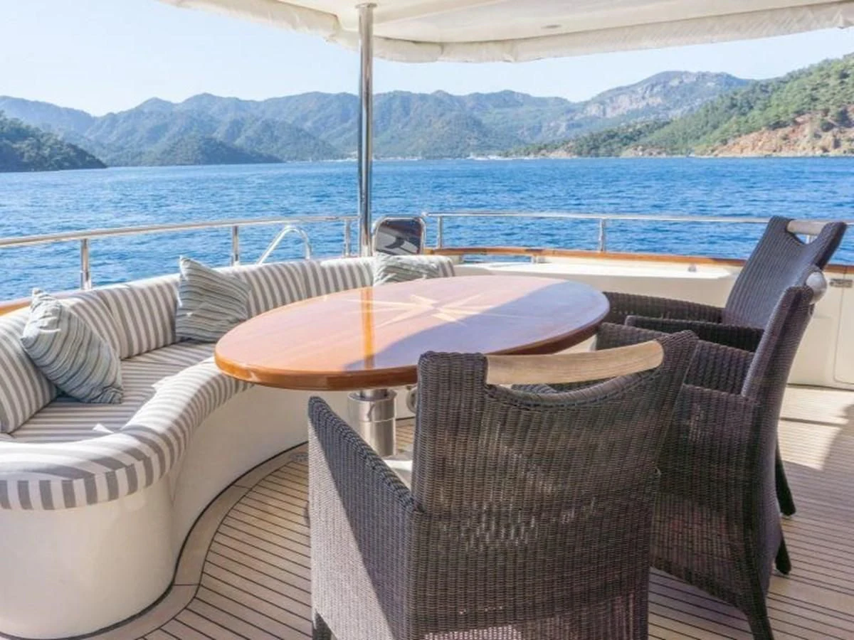 a table and chairs on a deck overlooking a body of water aboard STOLI Yacht for Sale