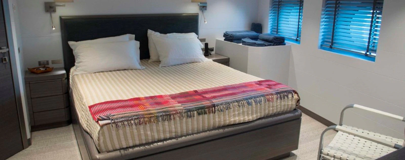 a bed with a red and white striped comforter and a white bed spread in a room with aboard OCEAN KING 130 Yacht for Sale
