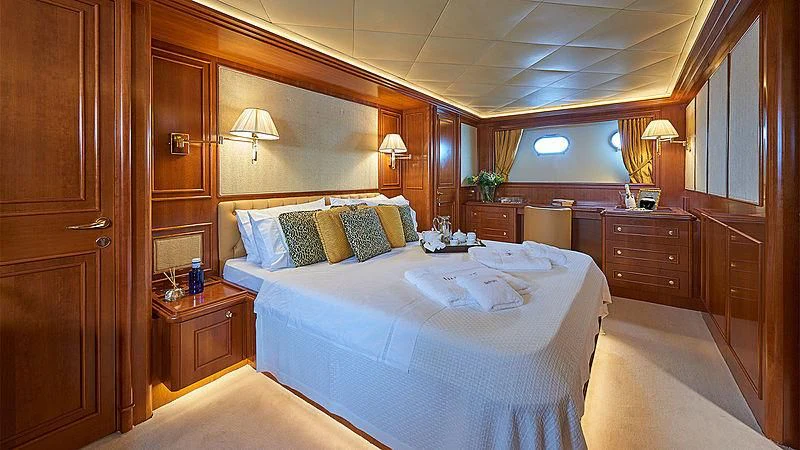 a room with a bed and a dresser aboard IMAGINE Yacht for Charter