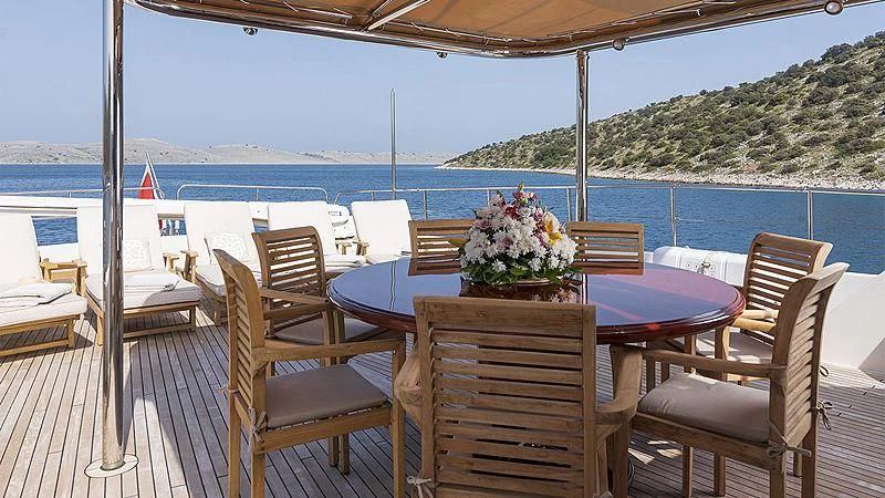 a table and chairs on a deck overlooking a body of water aboard IMAGINE Yacht for Charter