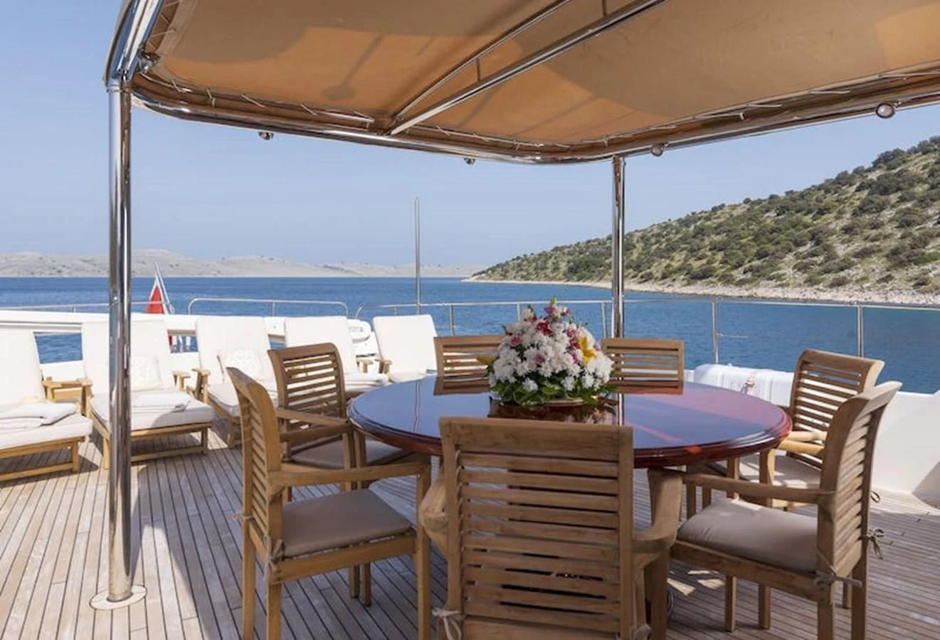 a table and chairs on a deck overlooking a body of water aboard IMAGINE Yacht for Charter