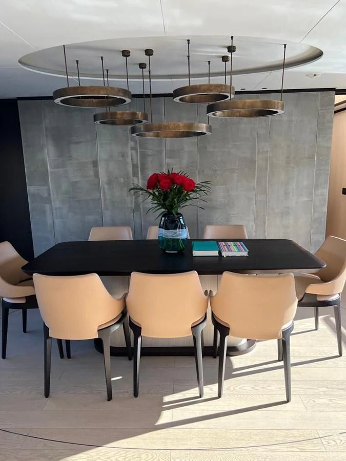 a dining room table with chairs and a vase of flowers on top aboard UNDICI Yacht for Sale