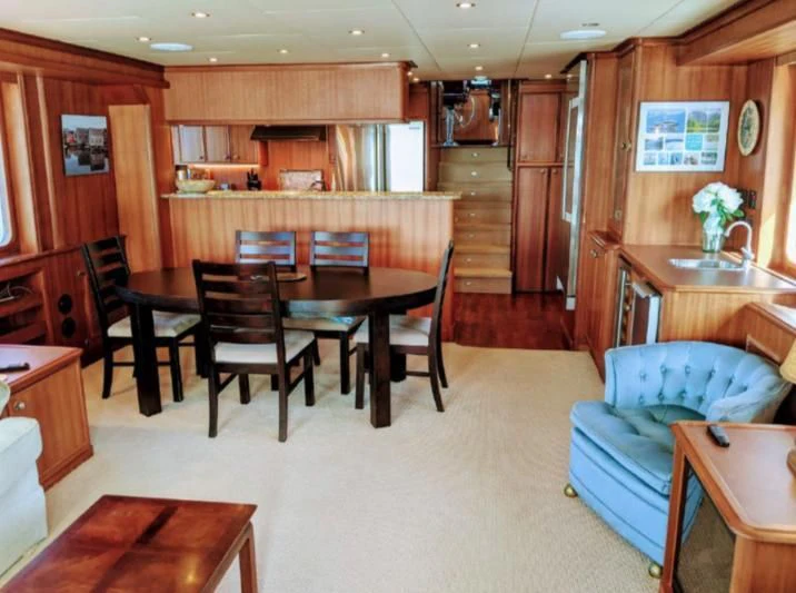 a room with a table chairs and a couch aboard IIWII Yacht for Sale