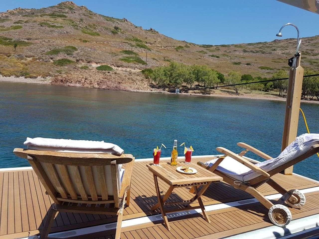 a table and chairs on a deck overlooking a body of water aboard PAREAKKI Yacht for Sale