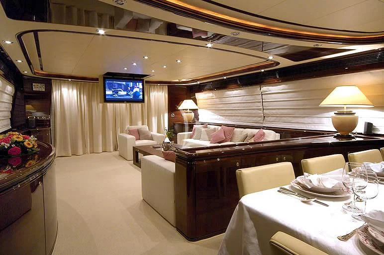 a room with a couch and a table with chairs and a television aboard TWO KAY Yacht for Sale