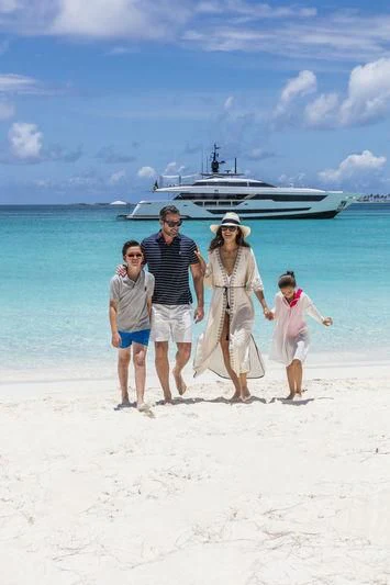 a family posing on a beach aboard NEVER BLUE Yacht for Sale