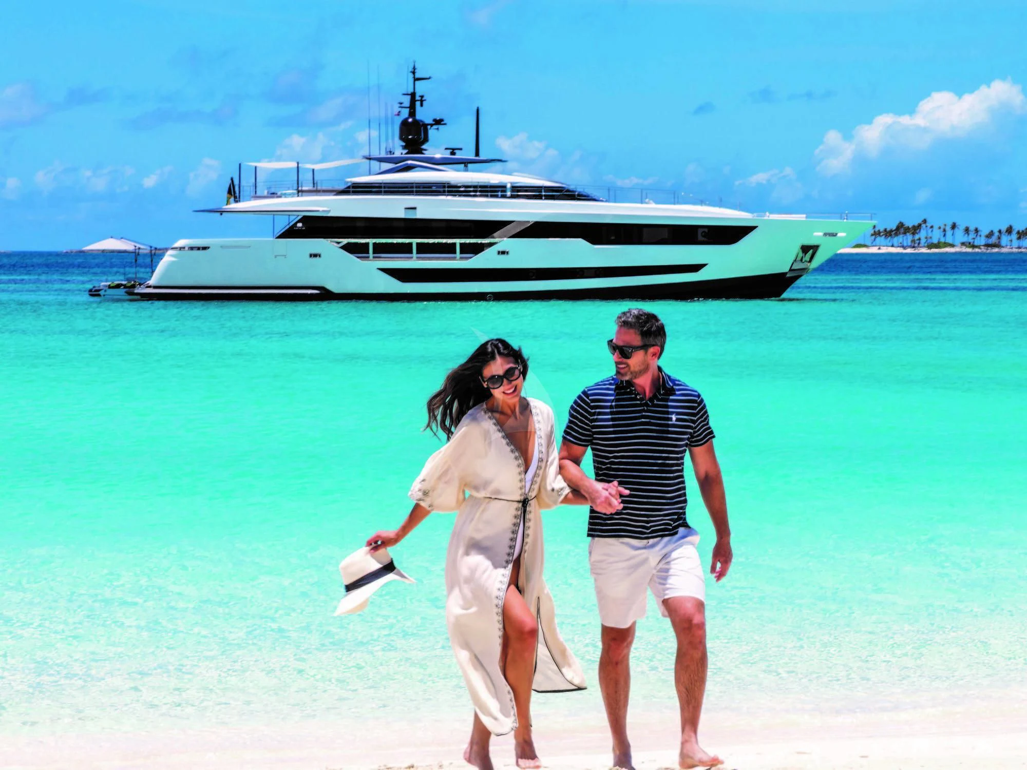 a group of people walking on a beach with a large ship in the background aboard NEVER BLUE Yacht for Sale