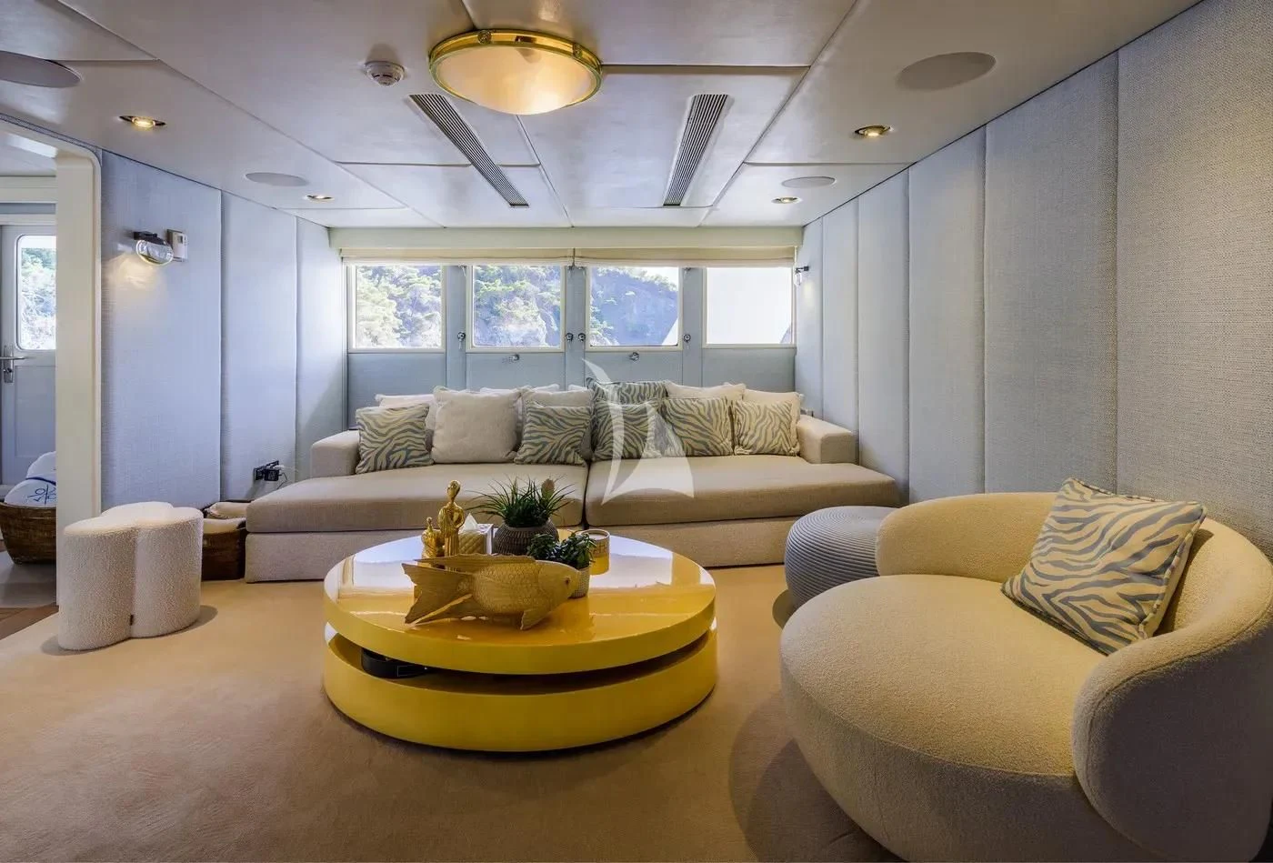 a living room with a large yellow table and white couches aboard ITOTO Yacht for Charter