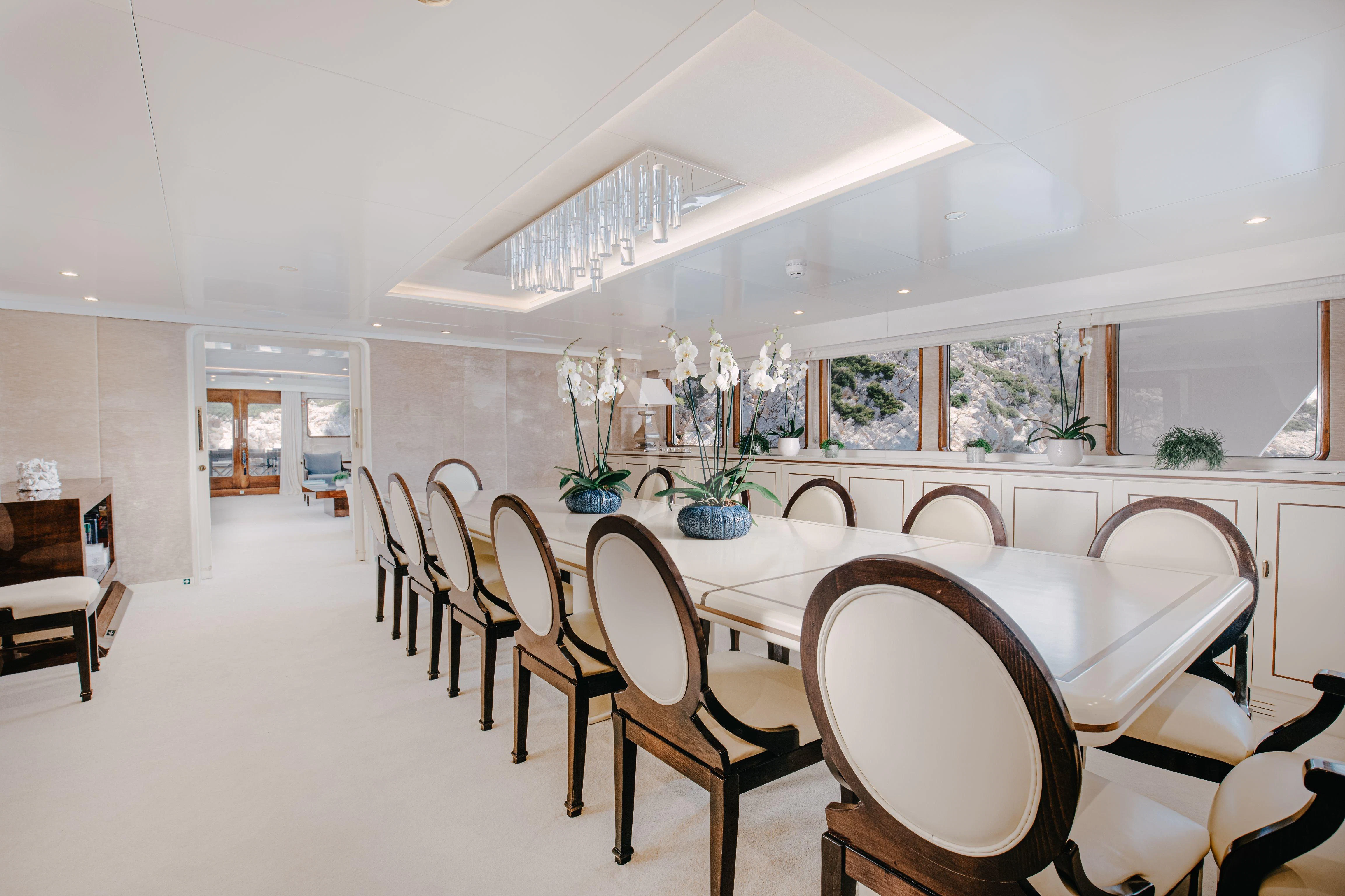 a dining room with white chairs aboard ITOTO Yacht for Charter
