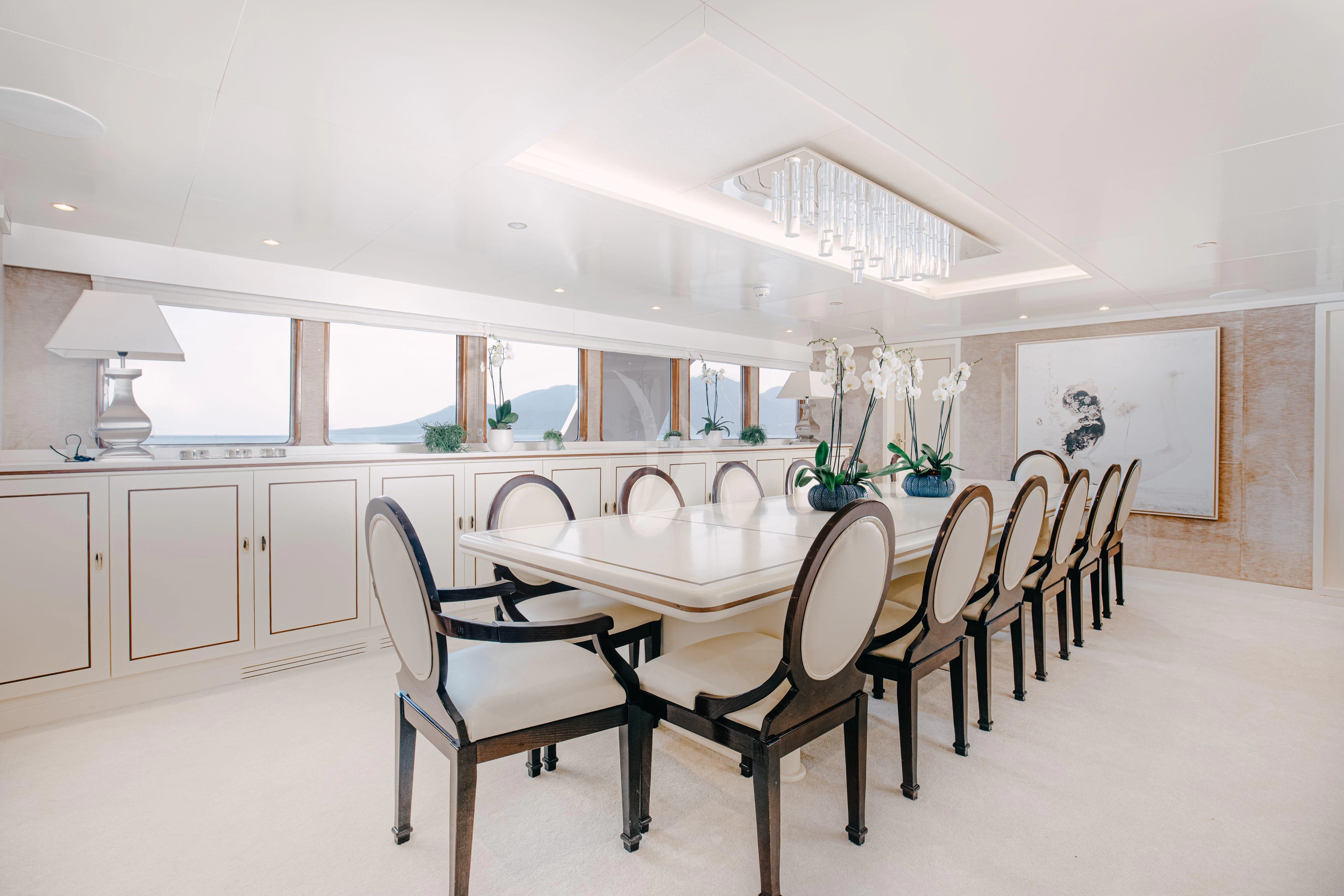 a dining table and chairs in a room with white walls aboard ITOTO Yacht for Charter