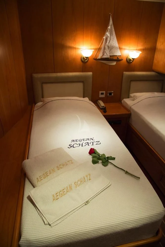 a bed with a white sheet and a white pillow with a rose on it aboard SCHATZ Yacht for Sale