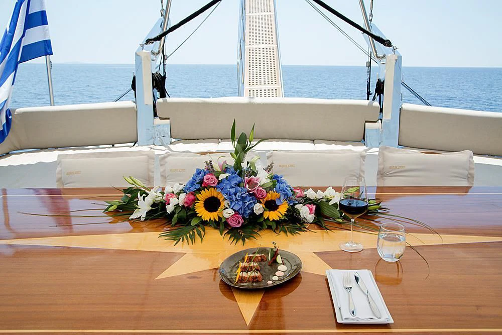 a table with a plate of flowers and a glass of wine on it aboard SCHATZ Yacht for Sale