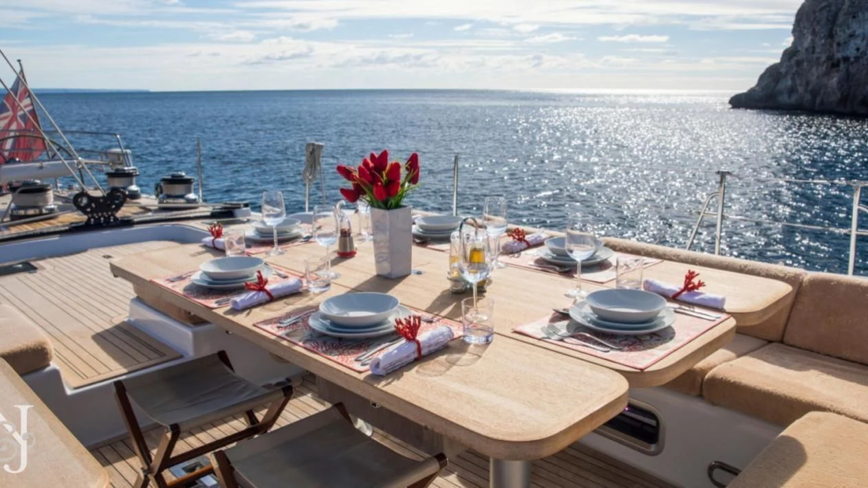 a table with plates and glasses on it by a body of water aboard MEDUSA Yacht for Sale