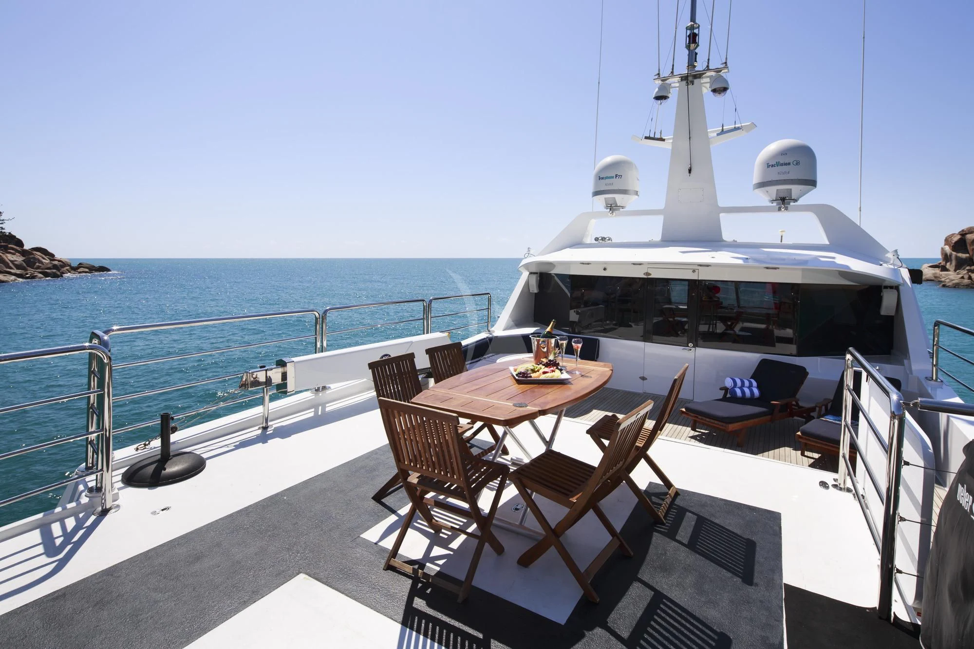 a table and chairs on a deck overlooking a boat on the water aboard FLYING FISH Yacht for Sale