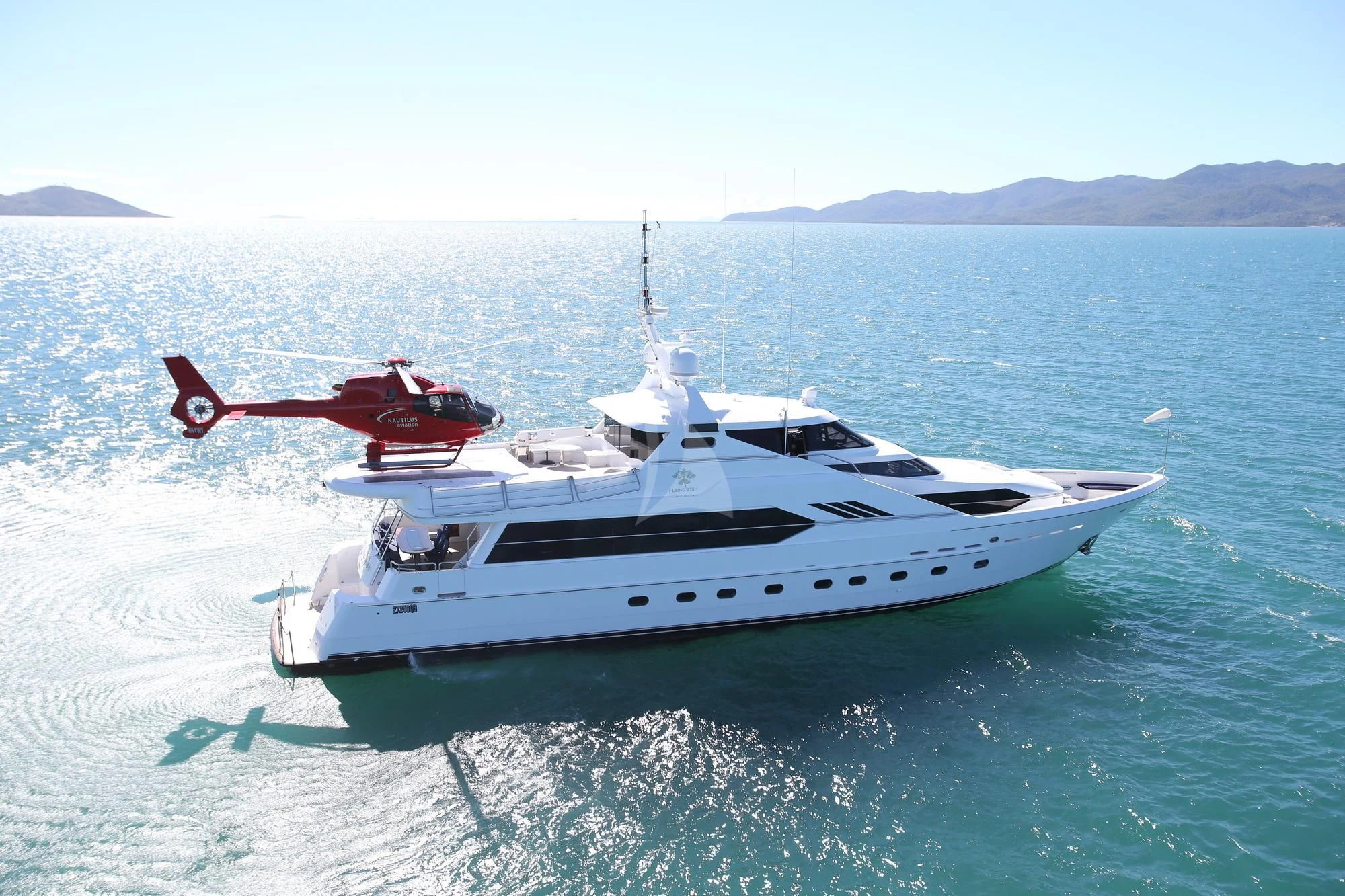 a helicopter flying over a boat in the water aboard FLYING FISH Yacht for Sale