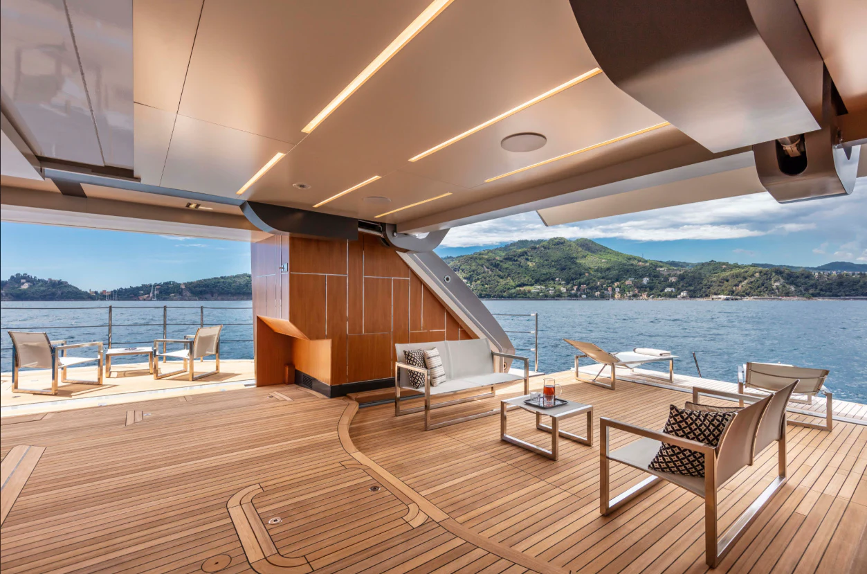 a deck with chairs and tables on it by a body of water aboard PERSHING 140 Yacht for Sale