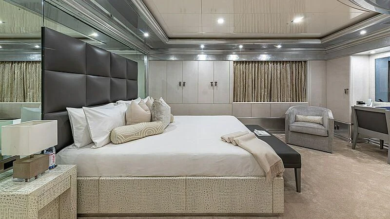 a large bedroom with a bed and a chair aboard ANDIAMO Yacht for Sale