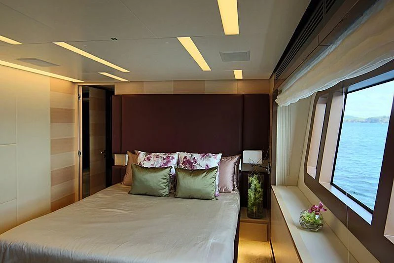 a bed with a white sheet and pillows in a room with a window aboard ESTEL OF IBIZA Yacht for Sale