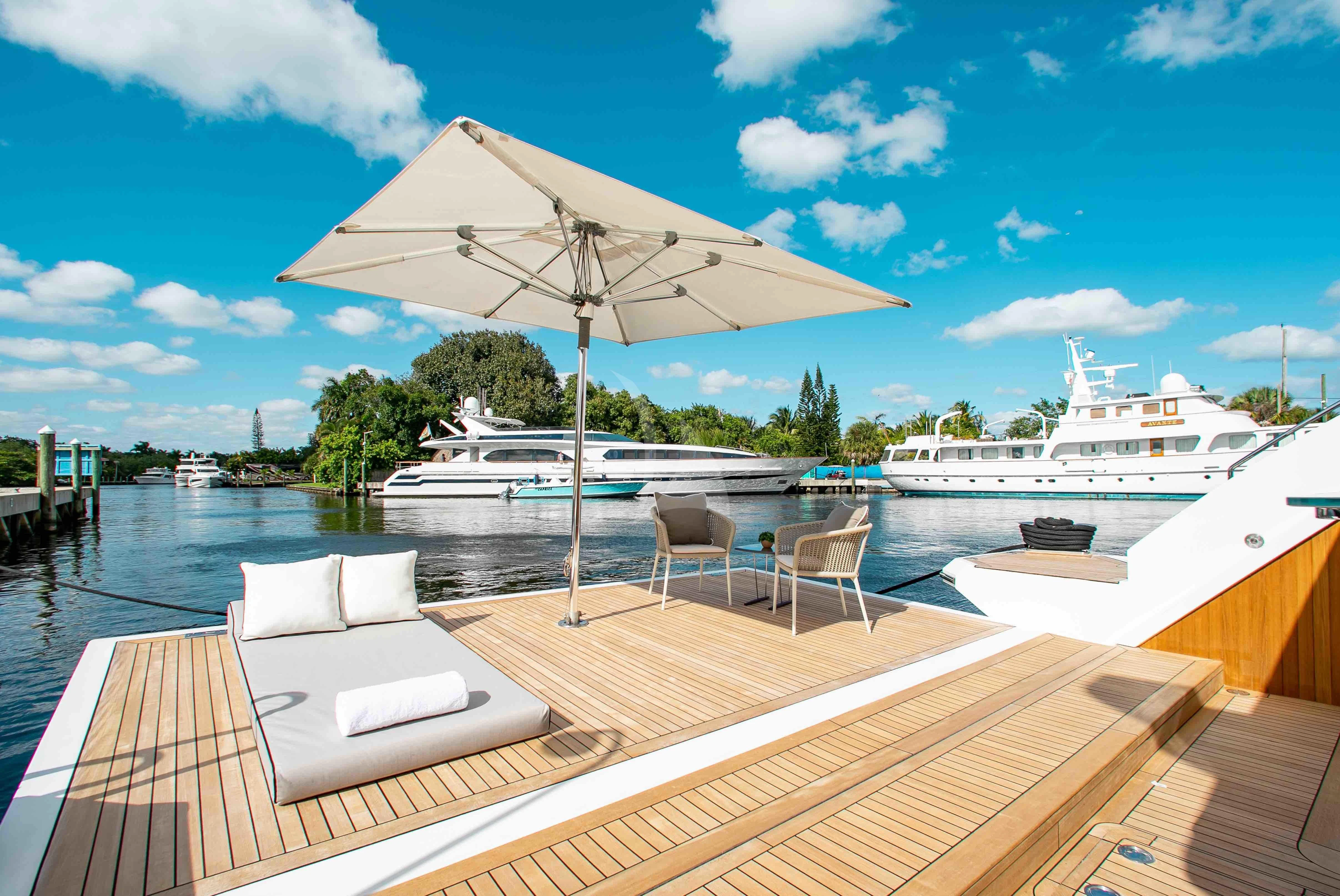 a deck with a white umbrella and chairs on it aboard EMINA Yacht for Charter