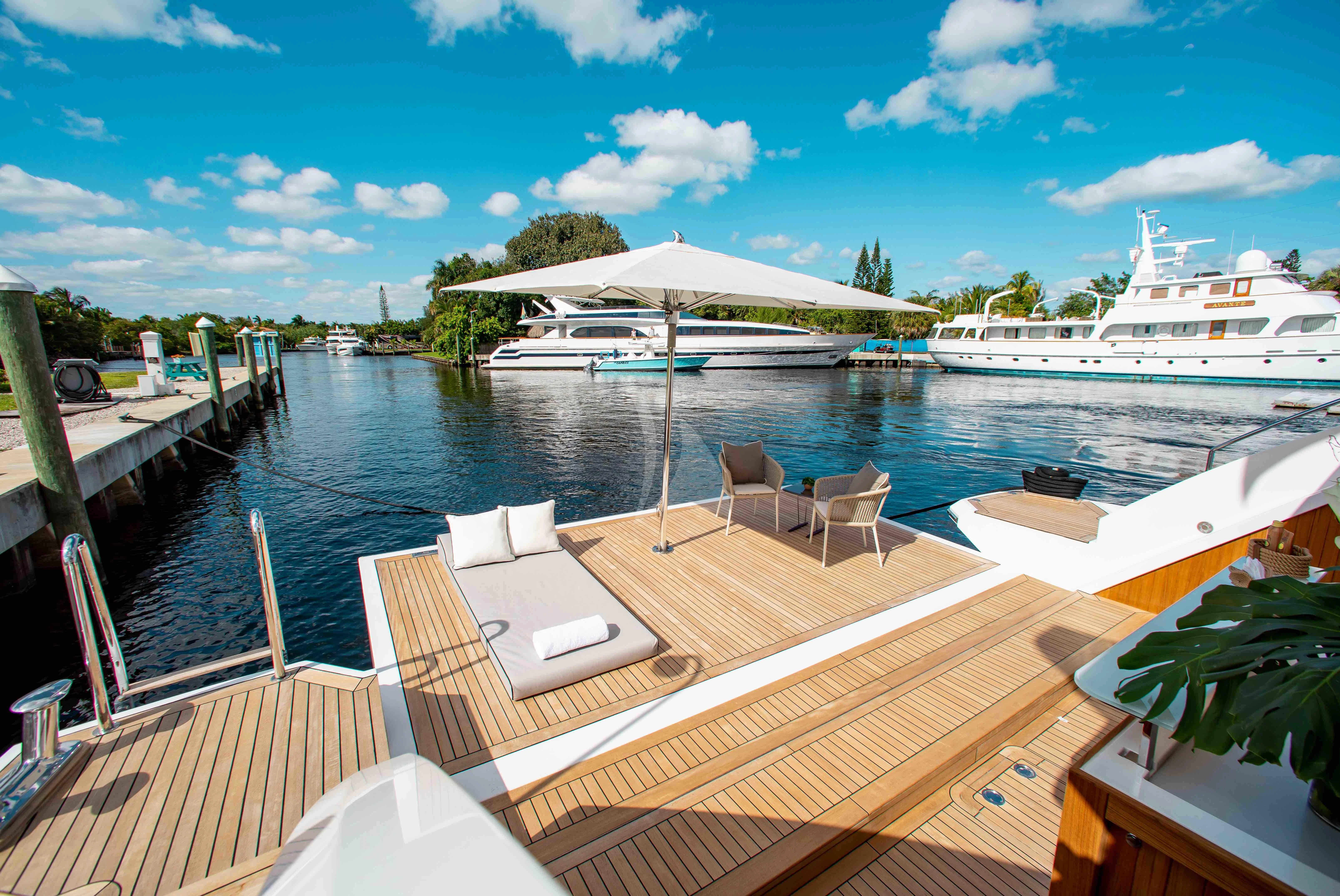 a deck with chairs and tables on it by a body of water aboard EMINA Yacht for Charter