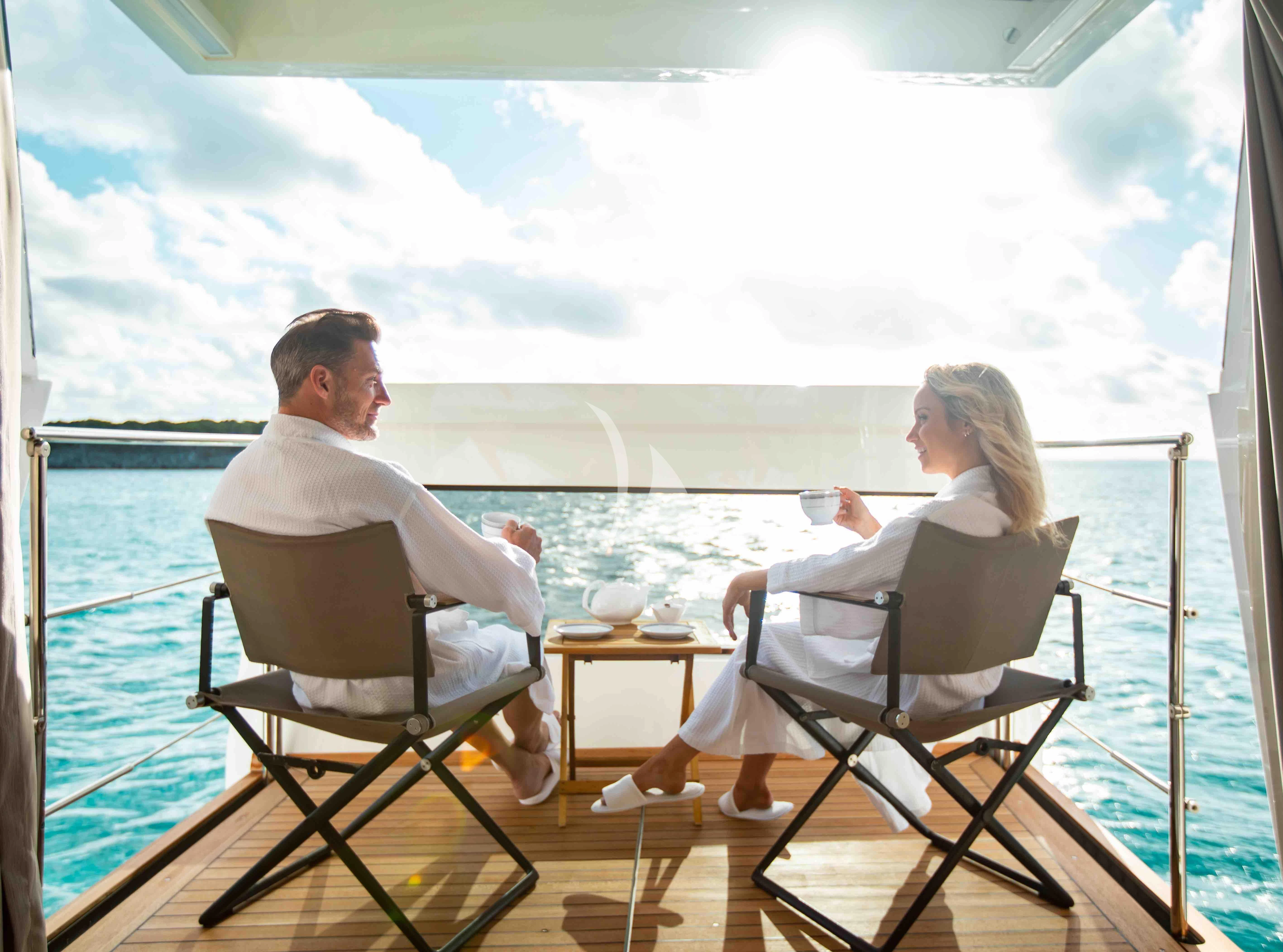 a man and a woman sitting on a boat looking out at the water aboard EMINA Yacht for Charter