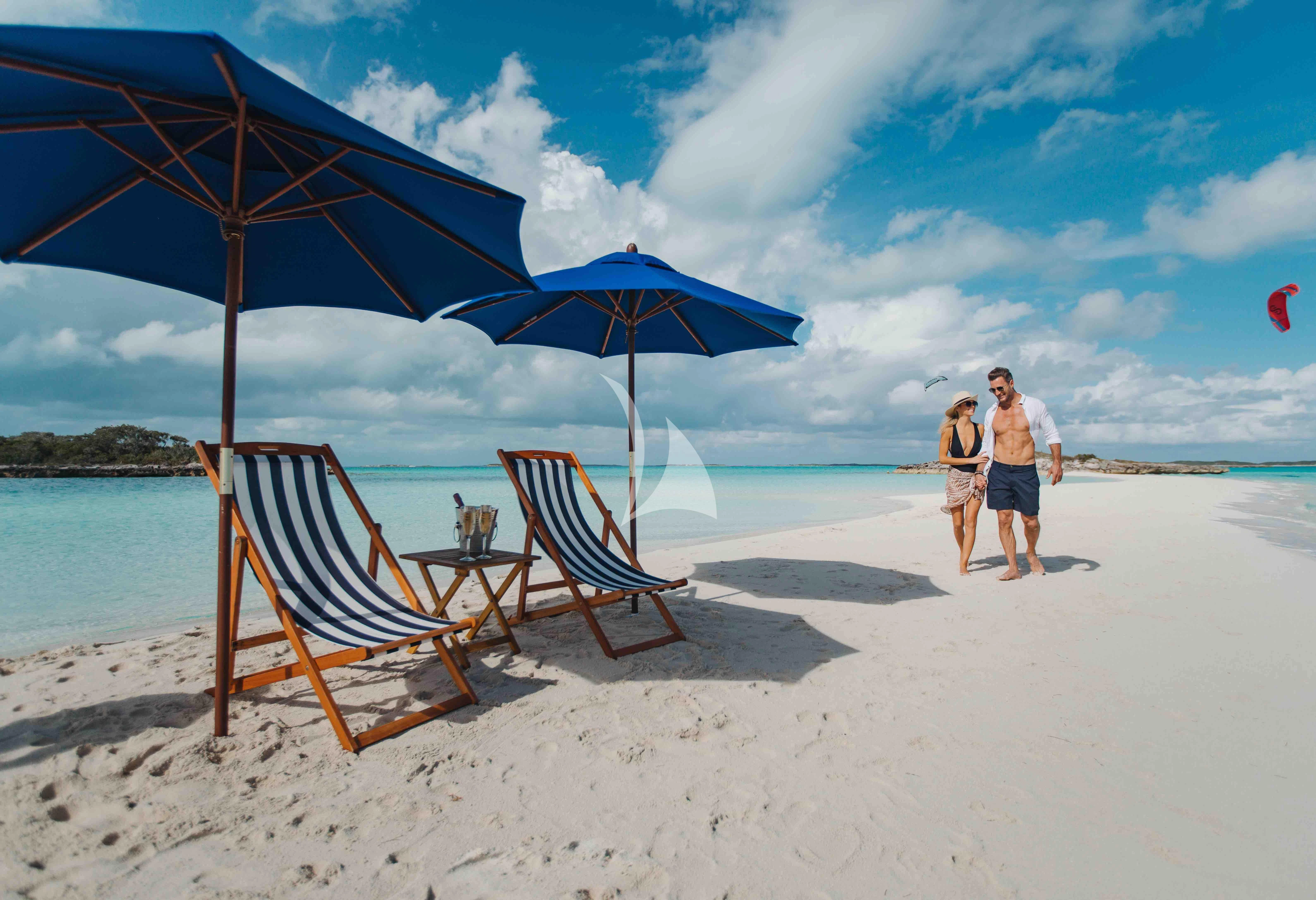 a couple of chairs and an umbrella on a beach aboard EMINA Yacht for Charter