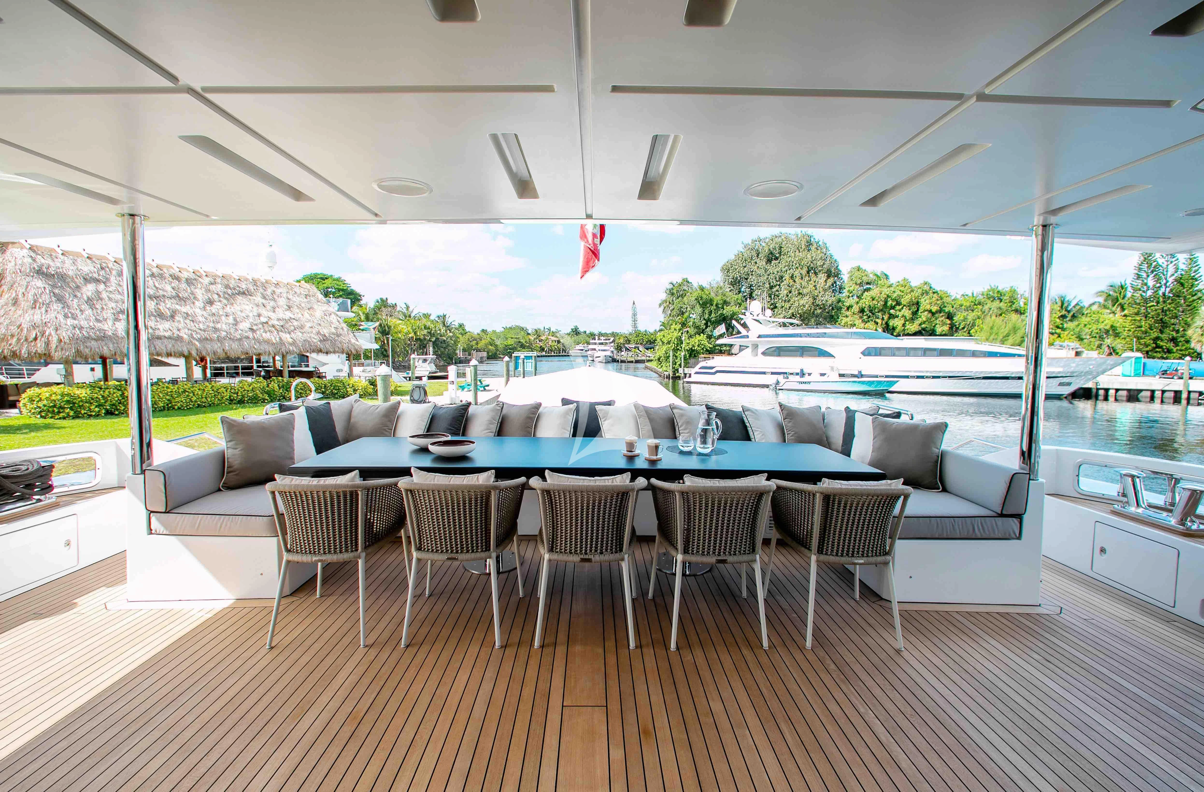 a large room with a table and chairs and a large window aboard EMINA Yacht for Charter