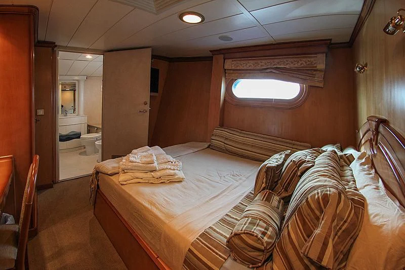 a bedroom with a bed and a window aboard PRINCESS OF PALAU Yacht for Sale
