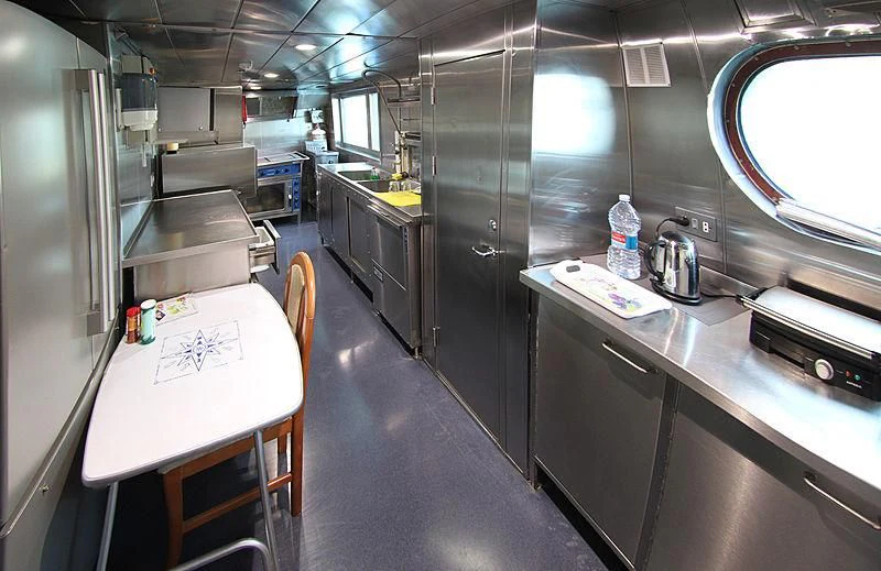 a kitchen with a table and chairs aboard PRINCESS OF PALAU Yacht for Sale
