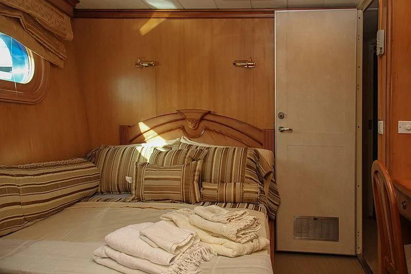 a bed with a white sheet and a brown door aboard PRINCESS OF PALAU Yacht for Sale