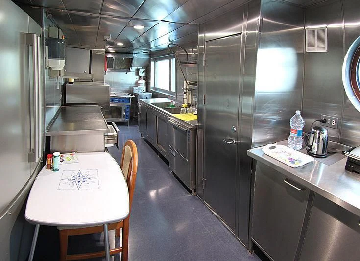 a kitchen with a table and chairs aboard PRINCESS OF PALAU Yacht for Sale