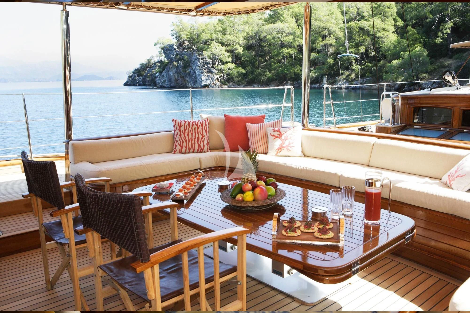 a table with chairs and a couch on a balcony overlooking a body of water aboard EUGENIA VII Yacht for Sale
