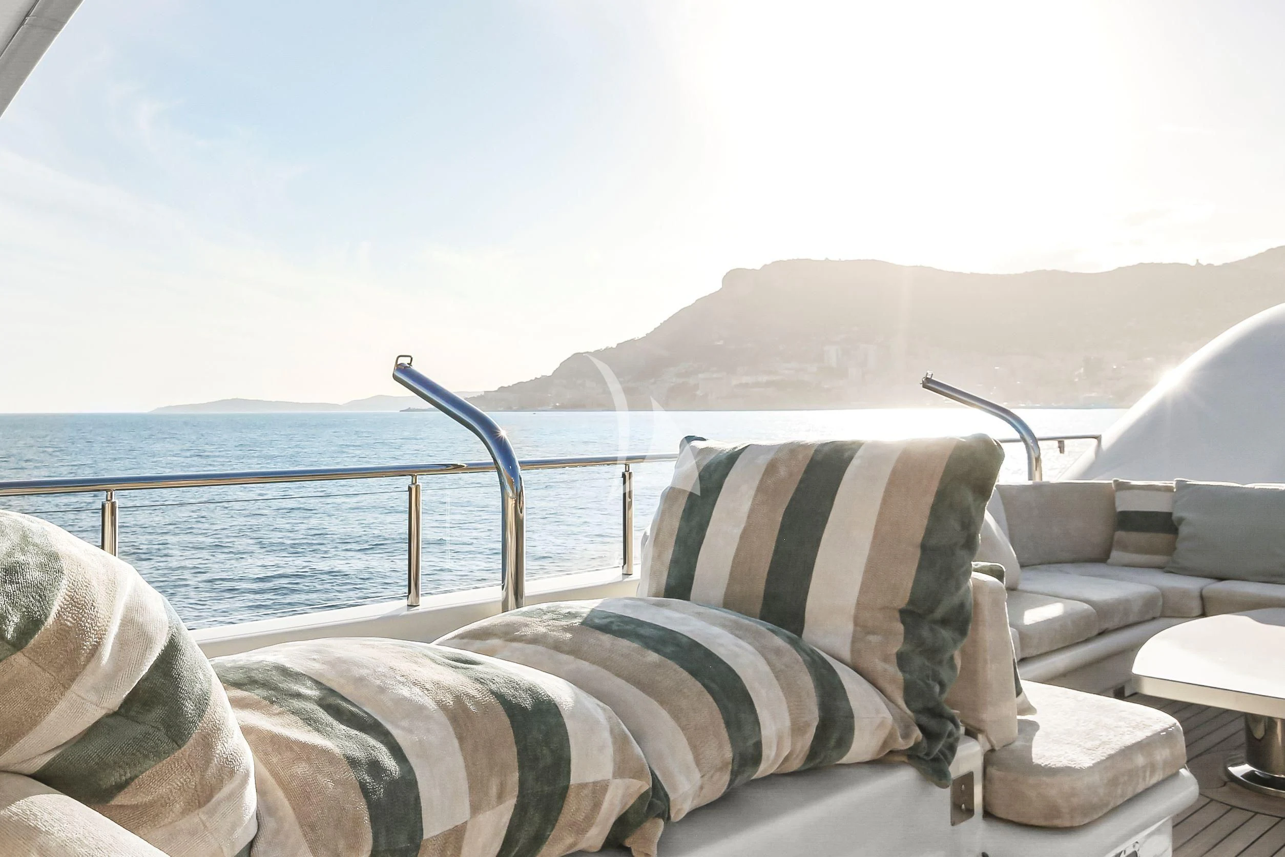 a couch and a chair on a balcony overlooking a body of water aboard SAMIRA Yacht for Sale