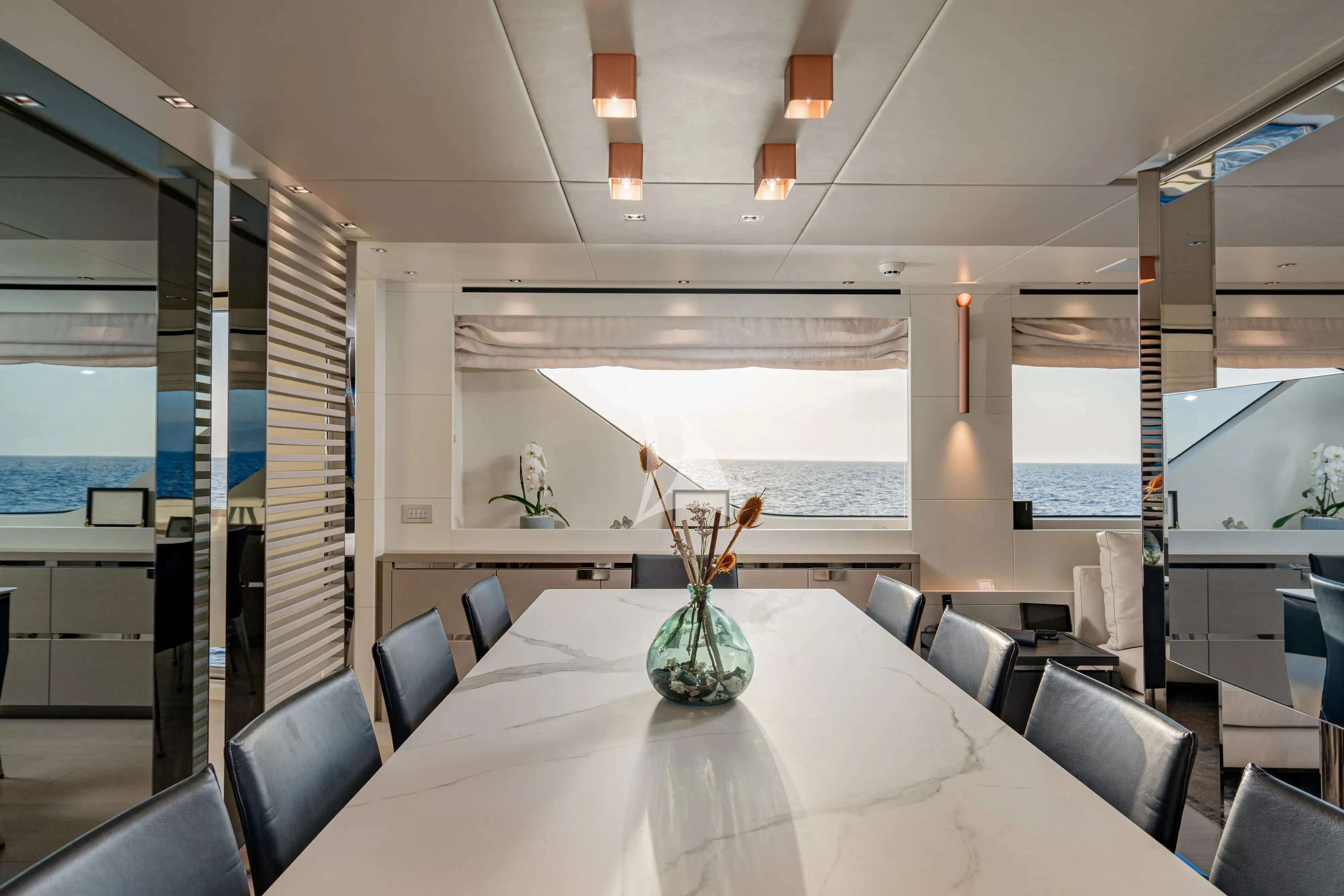a large room with chairs and a table with a vase on it aboard UNICKA Yacht for Sale