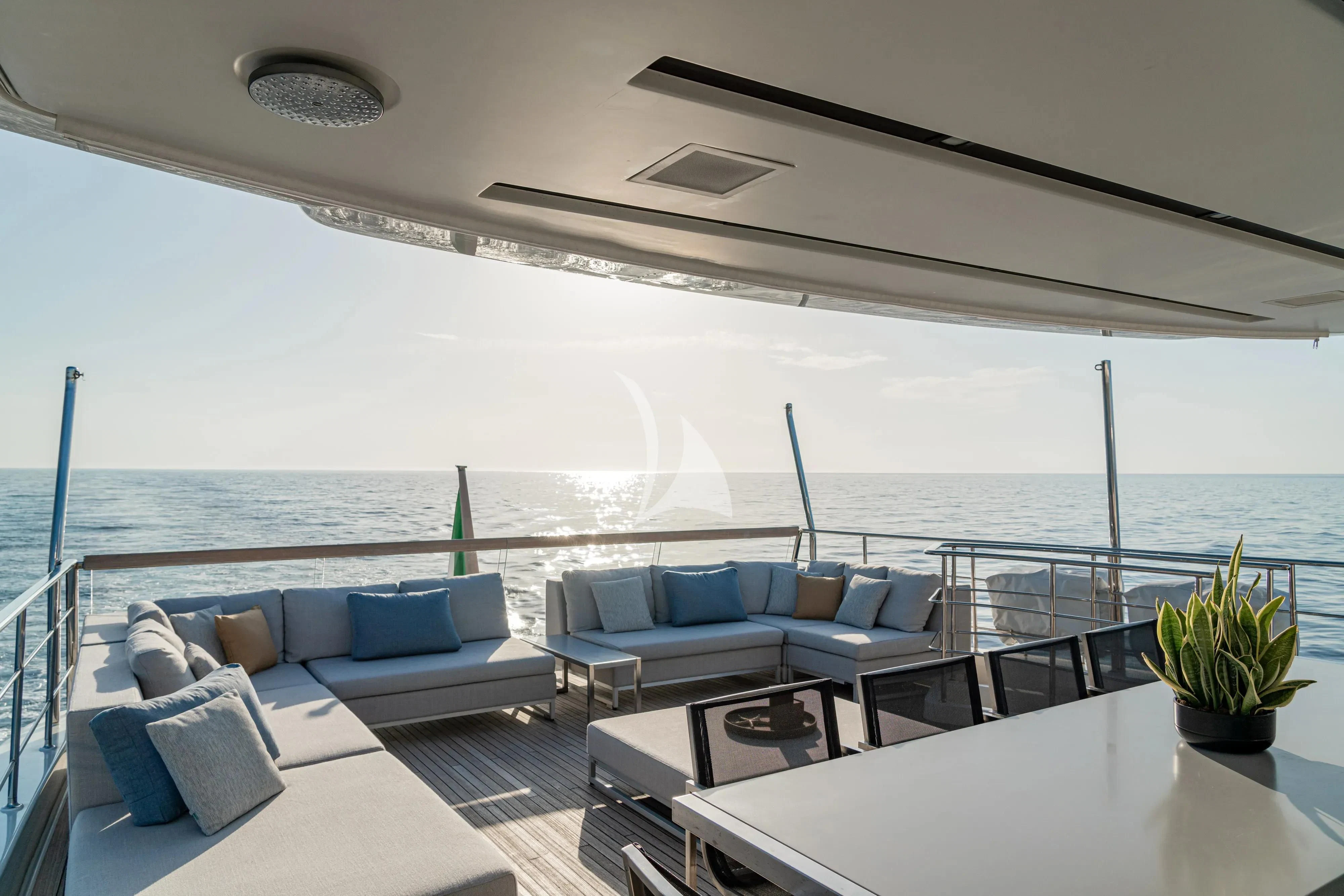 a large white lounge area with a large body of water in the background aboard UNICKA Yacht for Sale