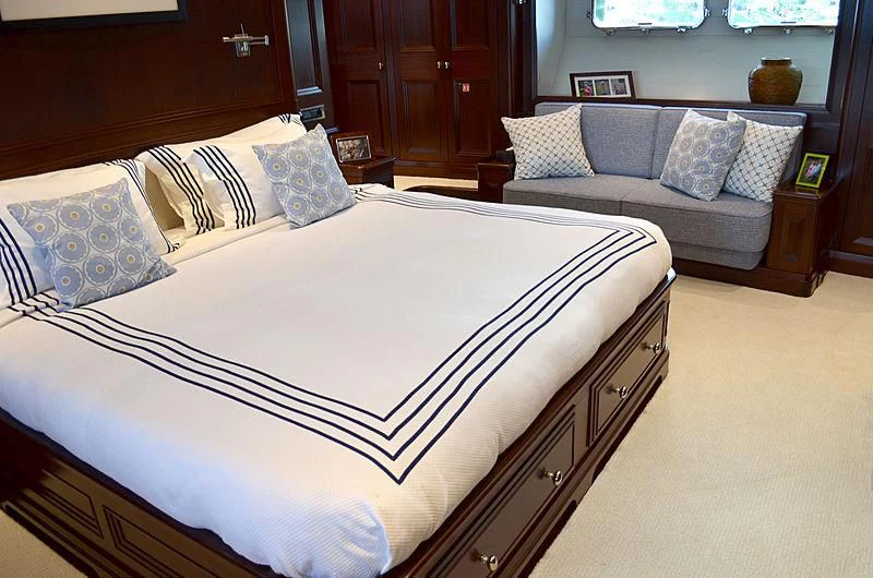 a bed with a white and blue blanket aboard LA BELLE Yacht for Sale
