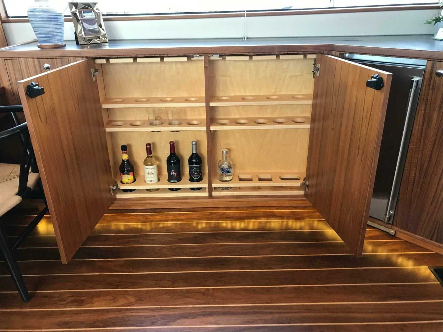 a wooden cabinet with bottles and glasses aboard PRIVATEER Yacht for Sale