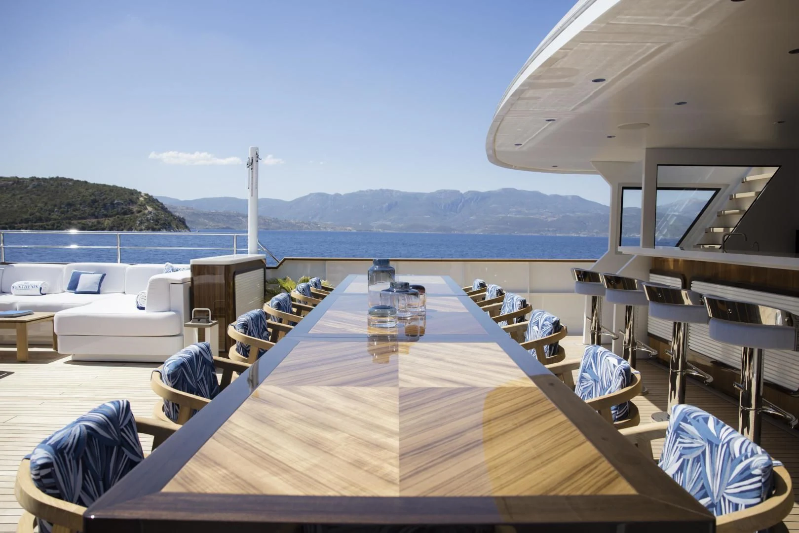 a deck with chairs and tables on it by the water aboard SYNTHESIS 66 Yacht for Sale