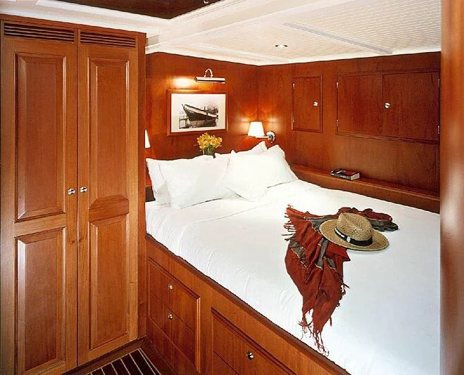 a bed with a white sheet and a wooden headboard aboard DOLPHIN Yacht for Sale