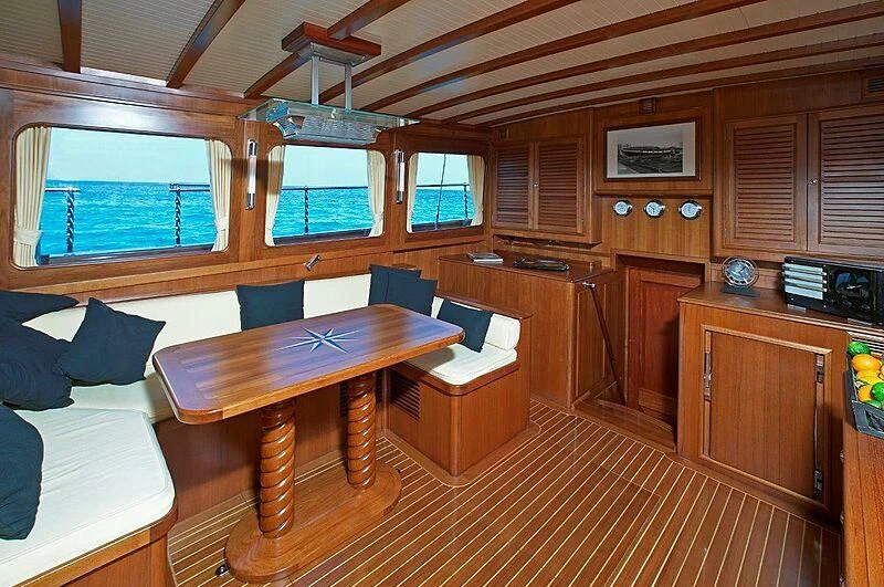 a cabin with a table and chairs aboard DOLPHIN Yacht for Sale