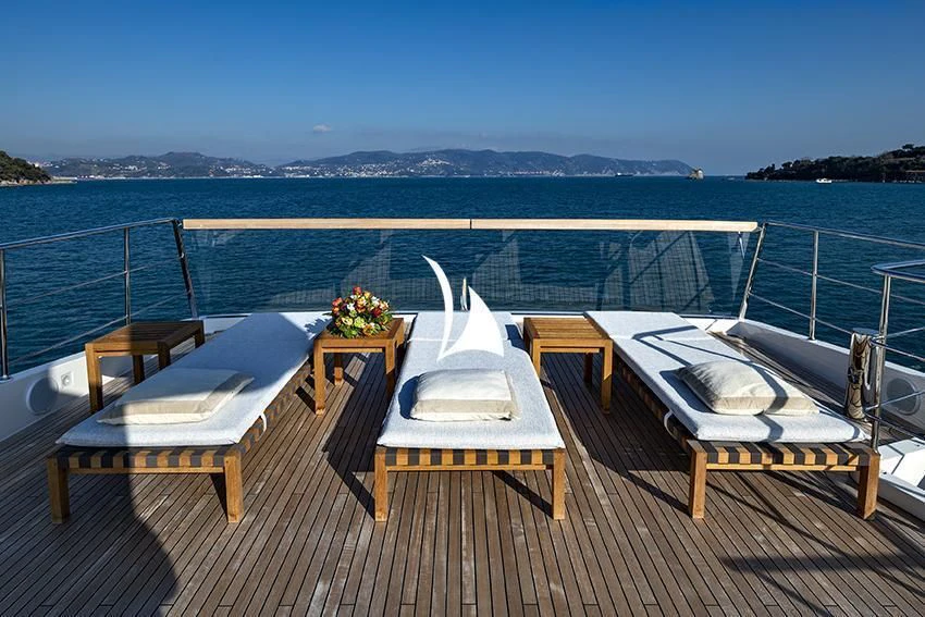 a deck with chairs and tables on it by the water aboard ANYTHING GOES V Yacht for Sale